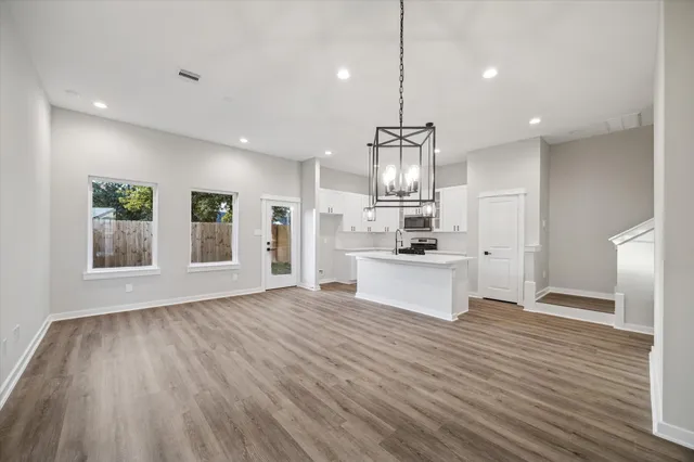 a large kitchen with kitchen island a stove a sink dishwasher and a refrigerator with wooden floor