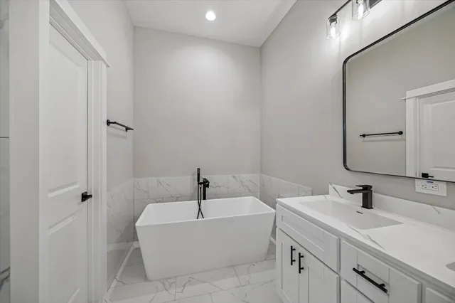 a bathroom with a tub sink and mirror
