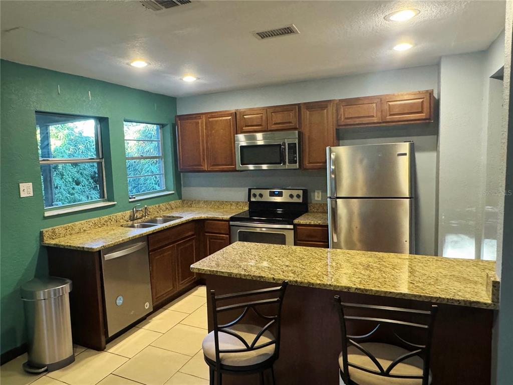 1030 East Walnut Street Lakeland, FL 33801 - Photo 4 of 11 a kitchen with stainless steel appliances granite countertop a sink stove and refrigerator