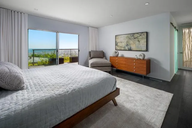 a bedroom with a bed a couch and large window