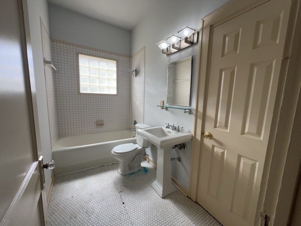 4716 Crawford Street Houston, TX 77004 - Photo 13 of 15 a bathroom with a sink a toilet a mirror and shower