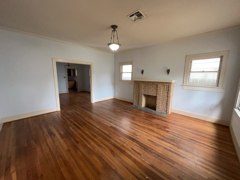 4716 Crawford Street Houston, TX 77004 - Photo 2 of 15 an empty room with wooden floor fireplace and windows