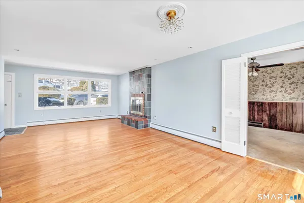 a view of an empty room with a window and wooden floor