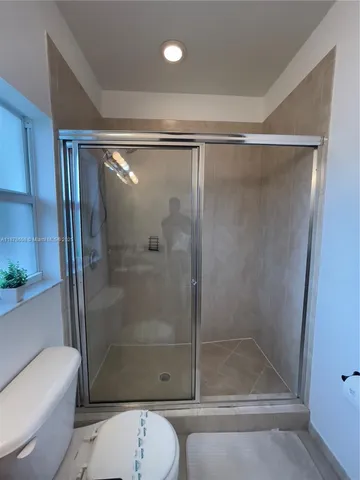 a bathroom with a shower a toilet and a glass door