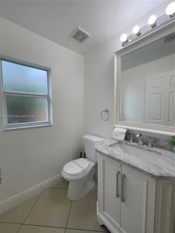 a bathroom with a granite countertop sink a toilet and a mirror
