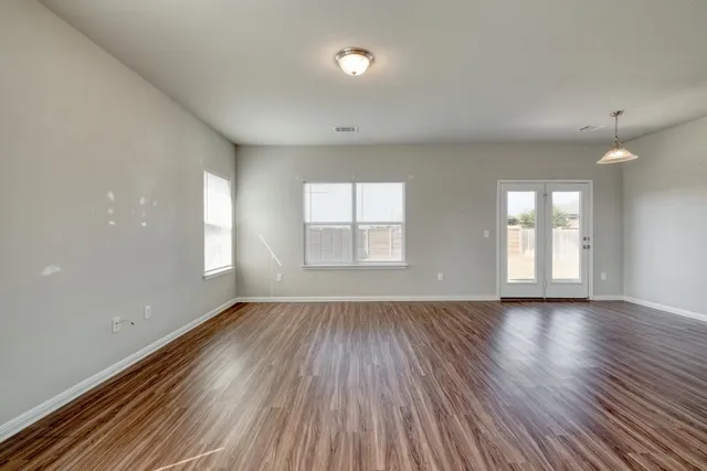 an empty room with wooden floor and windows