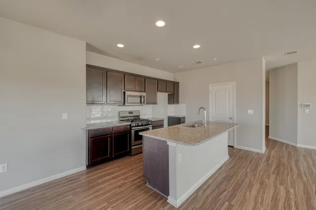 a large kitchen with stainless steel appliances granite countertop a sink and stove top oven