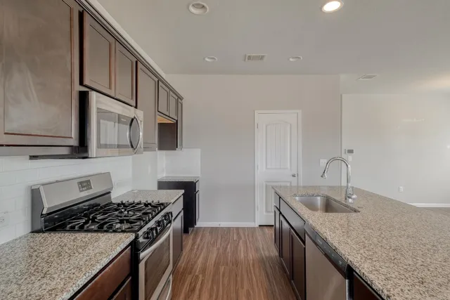 a kitchen that has a sink wooden cabinets and stainless steel appliances