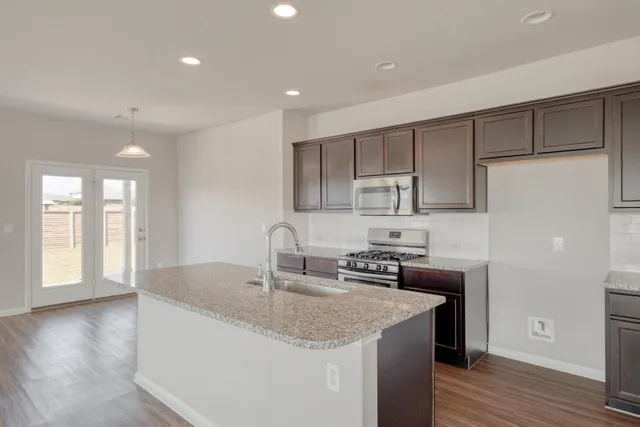 a kitchen with stainless steel appliances granite countertop a sink stove and refrigerator