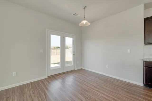 an empty room with wooden floor and windows