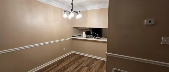 a view of a room with a hanging light and hardwood floor