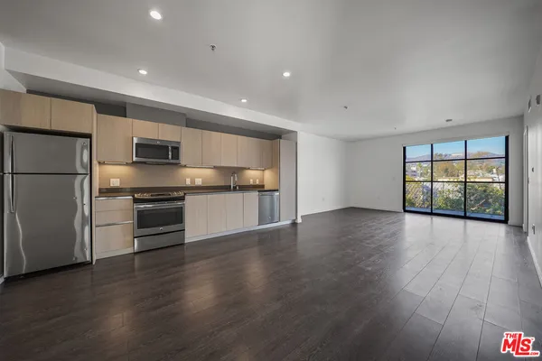 a kitchen with stainless steel appliances a refrigerator and wooden floor