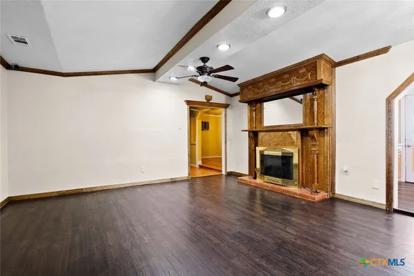 an empty room with wooden floor fireplace and windows
