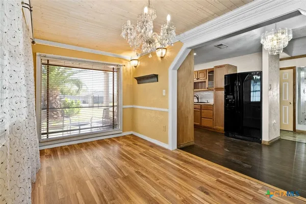 a view of a room with wooden floor chandelier and windows