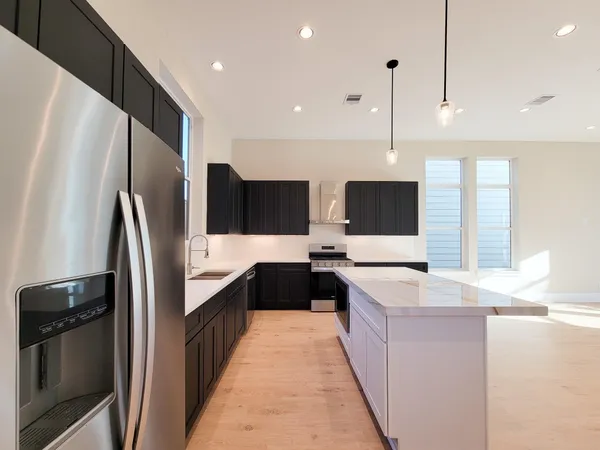 a large kitchen with stainless steel appliances a refrigerator a sink dishwasher a oven and a oven with wooden floor