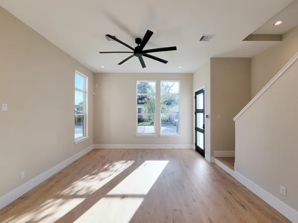 a view of empty room with wooden floor and fan