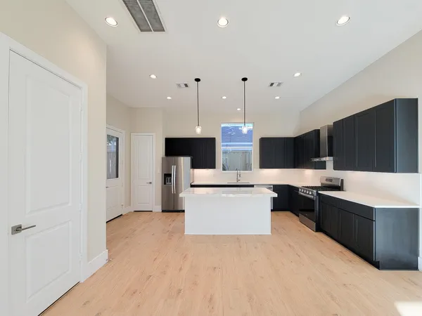 a open kitchen with kitchen island a sink a stove and a refrigerator