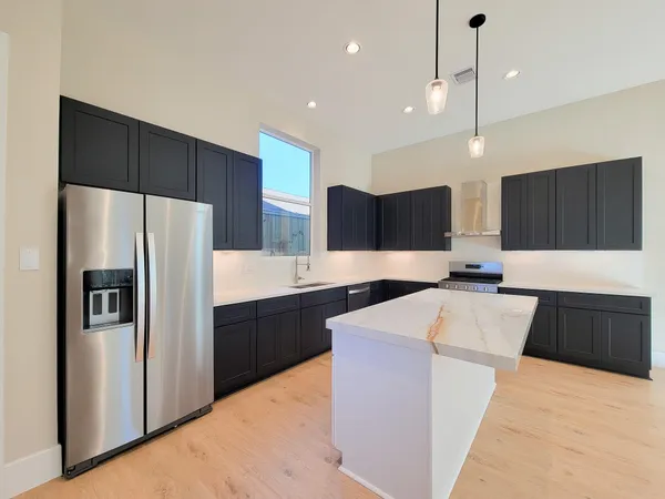 a large kitchen with stainless steel appliances kitchen island granite countertop a refrigerator a oven a sink and a counter top