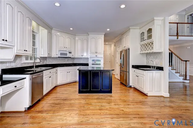 a large kitchen with stainless steel appliances granite countertop a stove a sink and a refrigerator