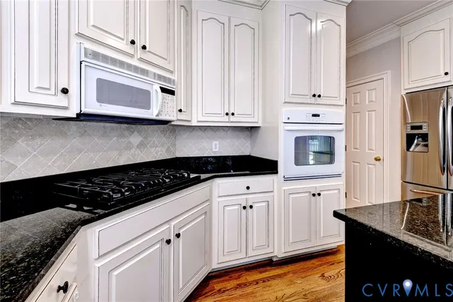 a kitchen with granite countertop white cabinets and black appliances