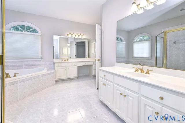 a spacious bathroom with a bathtub double sink and mirror