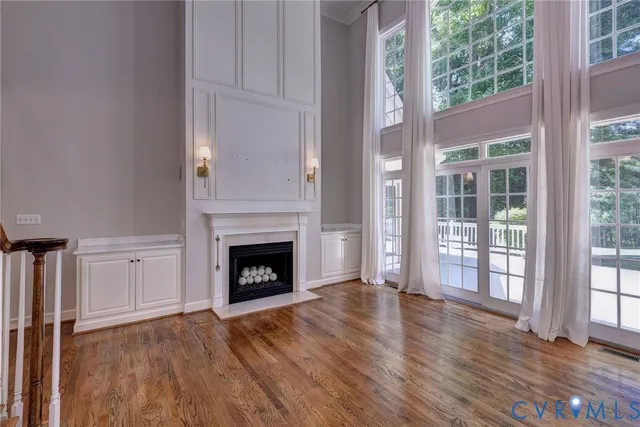an empty room with wooden floor fireplace and windows