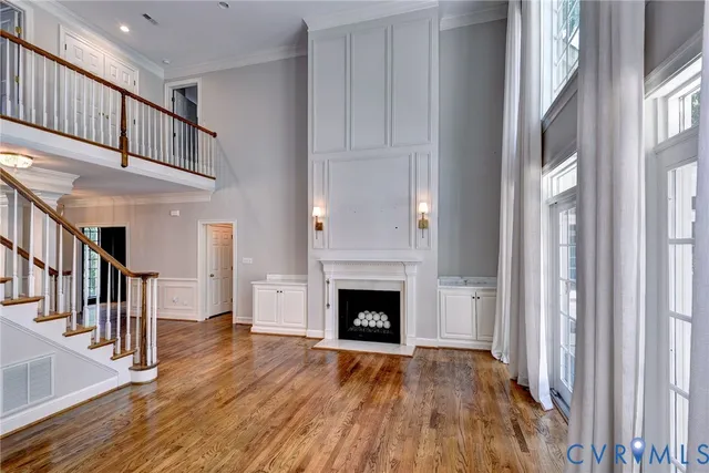 a view of an empty room with wooden floor fireplace and a window