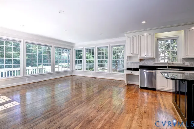 a kitchen with stainless steel appliances wooden floors and white cabinets