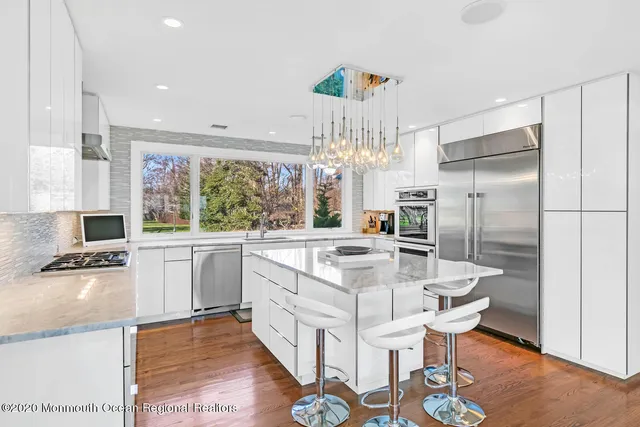 a large white kitchen with a large window a sink and stainless steel appliances