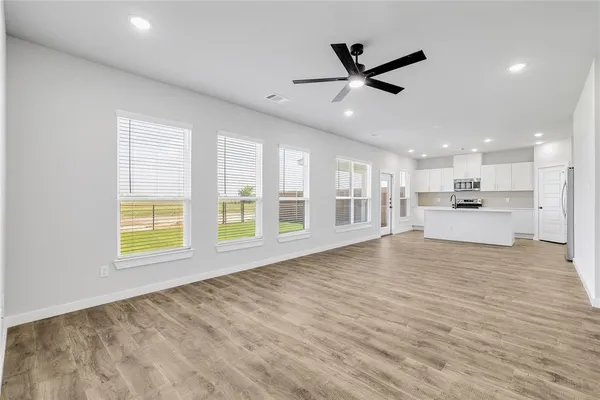 a view of an empty room with a window and a kitchen