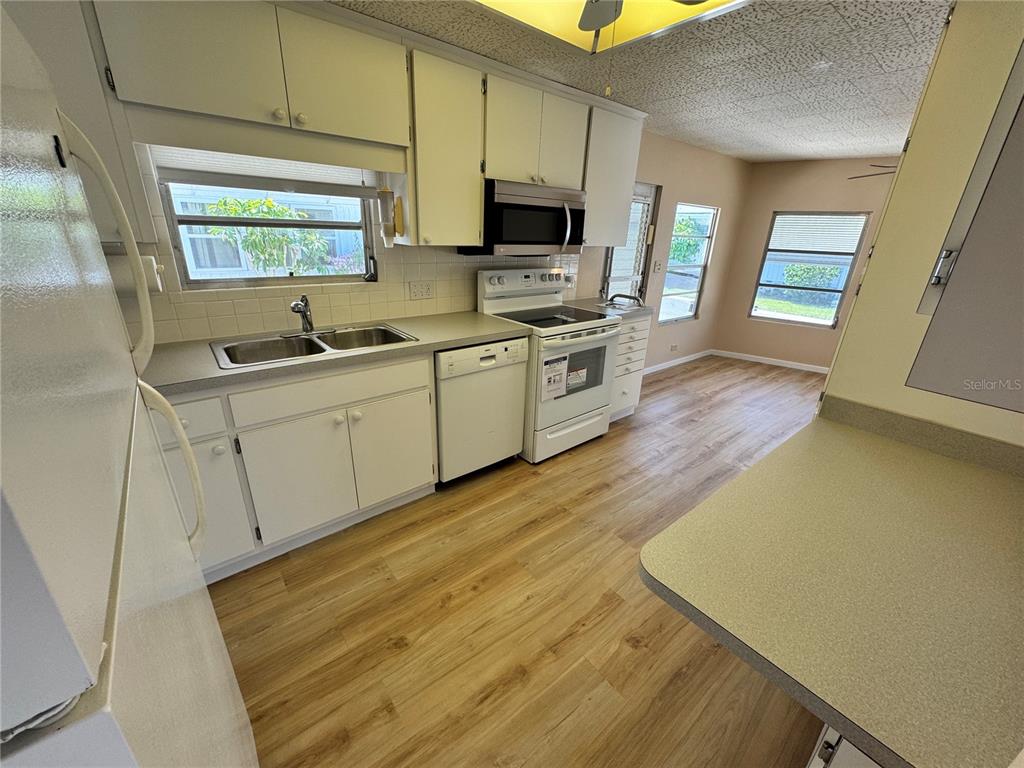 2331 Belleair Road, Unit LOT 237 Clearwater, FL 33764 - Photo 11 of 33 a kitchen with wooden floors and white appliances
