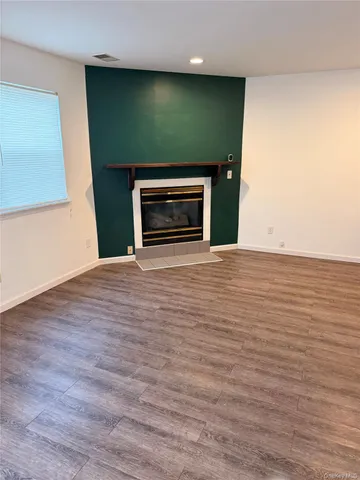 a view of an empty room with wooden floor and a fireplace