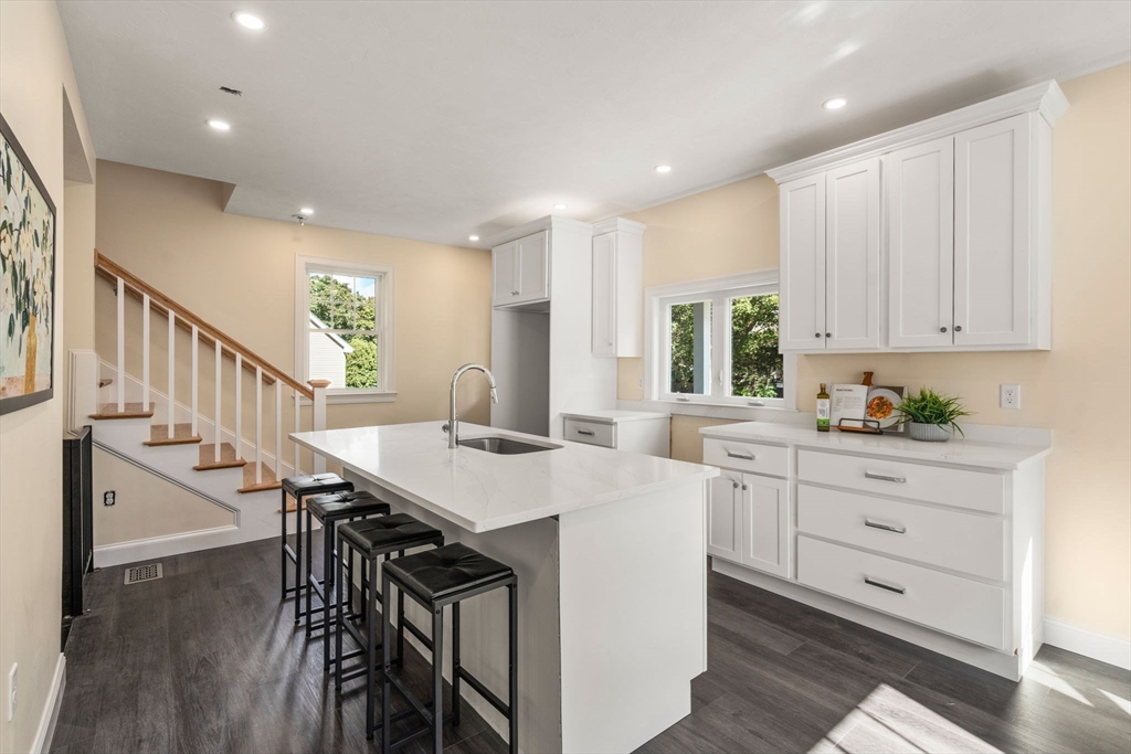 28 Waltham Street, Unit B Maynard, MA 01754 - Photo 5 of 17 a kitchen with stainless steel appliances kitchen island wooden floors and white cabinets