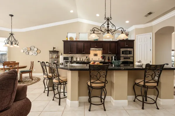 a kitchen with stainless steel appliances granite countertop a stove a sink a dining table and chairs with wooden floor
