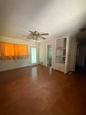 an empty room with windows and chandelier fan