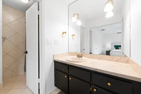 a en suite bathroom with a granite countertop sink and a mirror