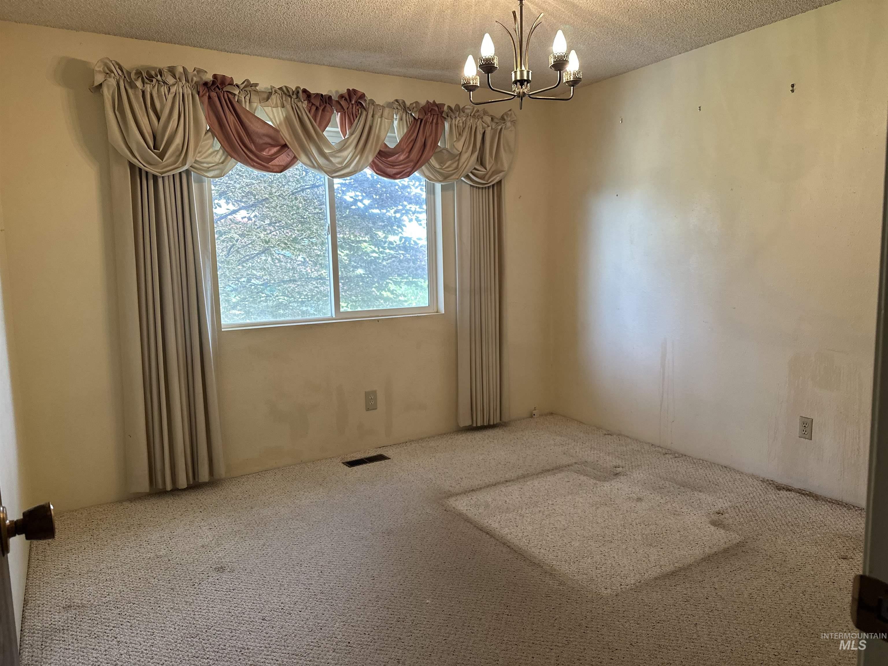 1620 6th Avenue Clarkston, WA 99403 - Photo 11 of 19 Room featuring a multi-pane window with drapery, wall-to-wall carpeting, and a ceiling-mounted chandelier