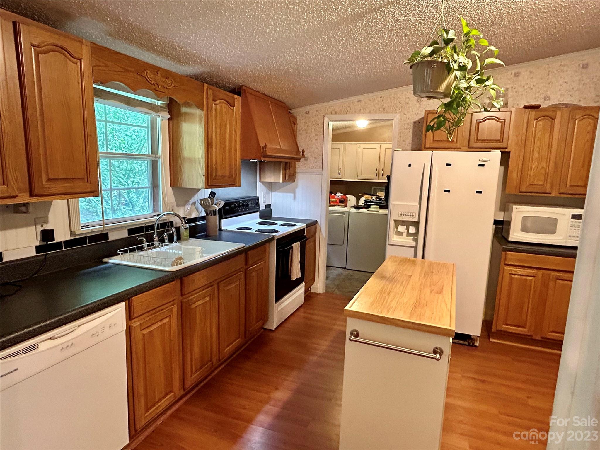 71 Bear Trail Fairview, NC 28730 - Photo 15 of 42 a kitchen with granite countertop a refrigerator a sink dishwasher and white cabinets with wooden floor