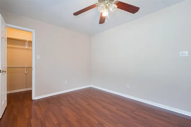 an empty room with wooden floor and chandelier fan