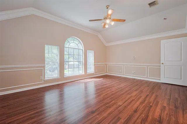 an empty room with wooden floor chandelier fan and windows
