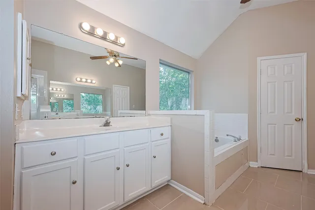 a bathroom with a sink a large mirror and a bathtub next to a window
