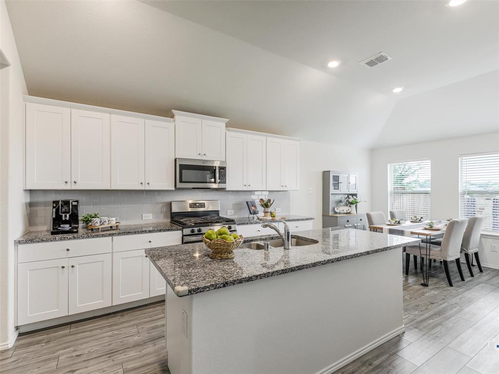 4517 Ashmark Road Aubrey, TX 76227 - Photo 19 of 26 a open kitchen with granite countertop a stove top oven a sink a counter space and cabinets