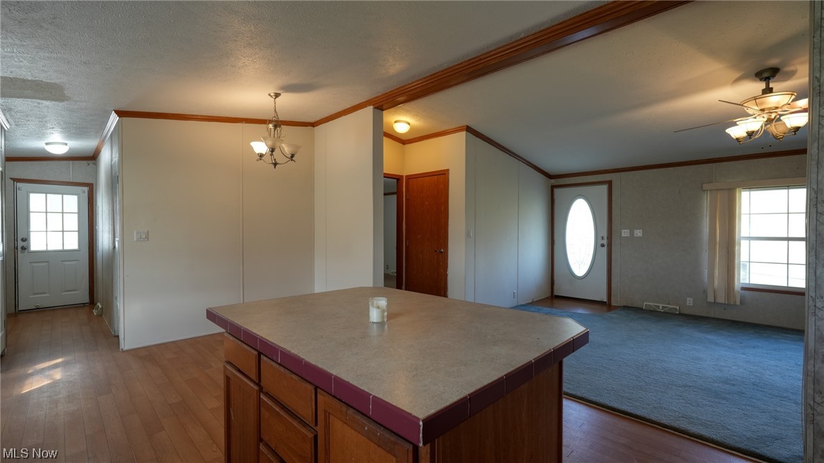 59062 Marietta Road Byesville, OH 43723 - Photo 8 of 33 Kitchen featuring ceiling fan with notable chandelier, carpet, a textured ceiling, crown molding, and hanging light fixtures