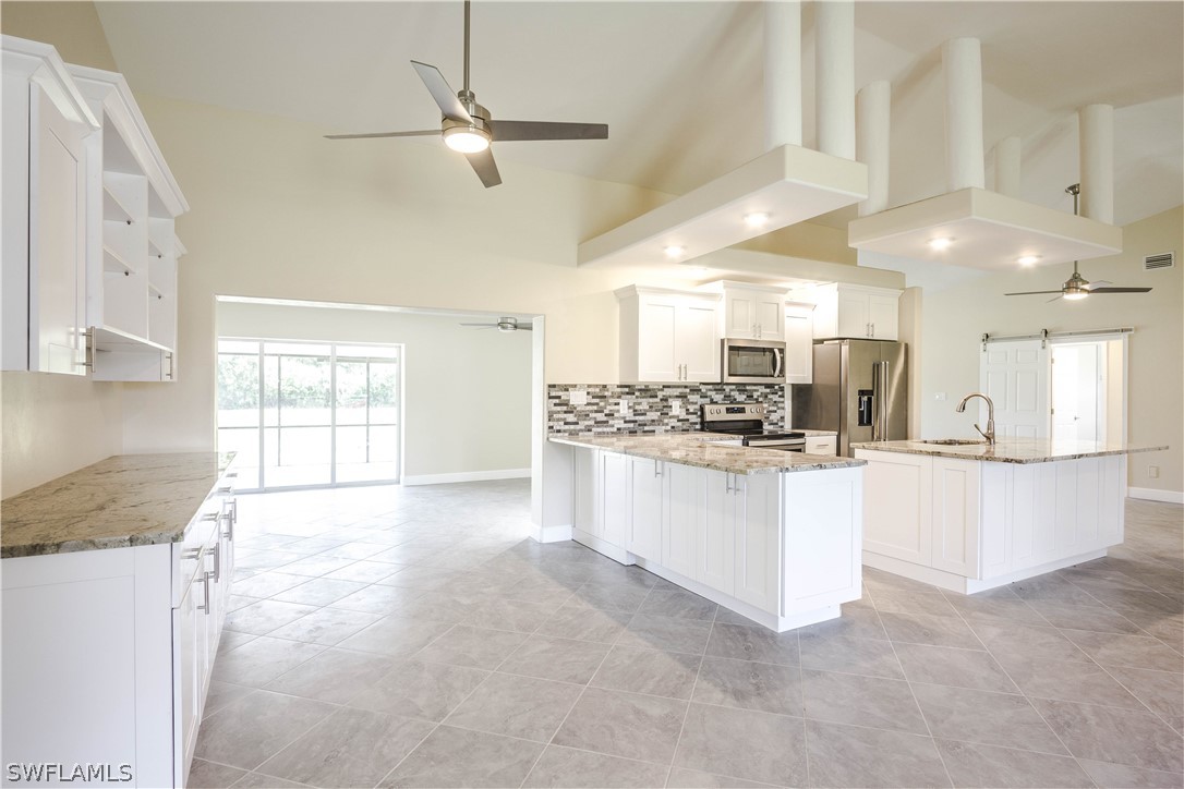 2871 Styles Road Alva, FL 33920 - Photo 6 of 33 a large white kitchen with kitchen island a stove a sink a refrigerator and white cabinets