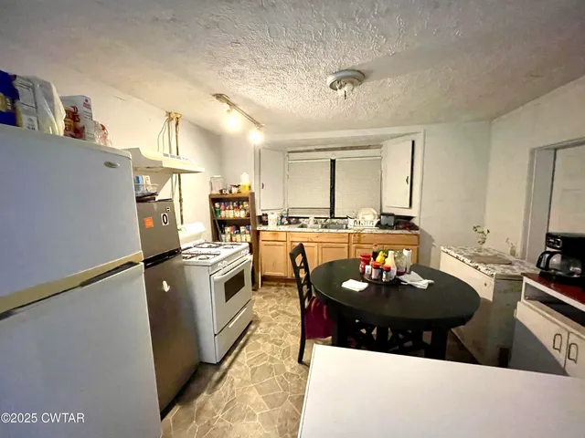 a kitchen with sink a refrigerator and chairs