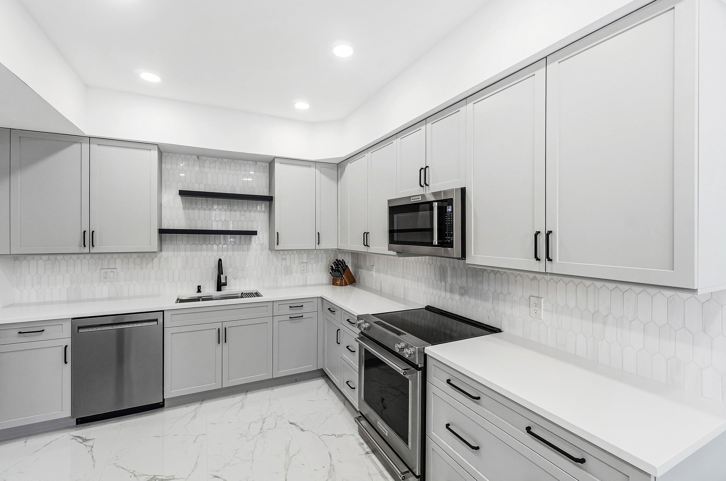 5082 Lake Catalina Drive, Unit A Boca Raton, FL 33496 - Photo 7 of 35 a kitchen with stainless steel appliances a sink stove and microwave
