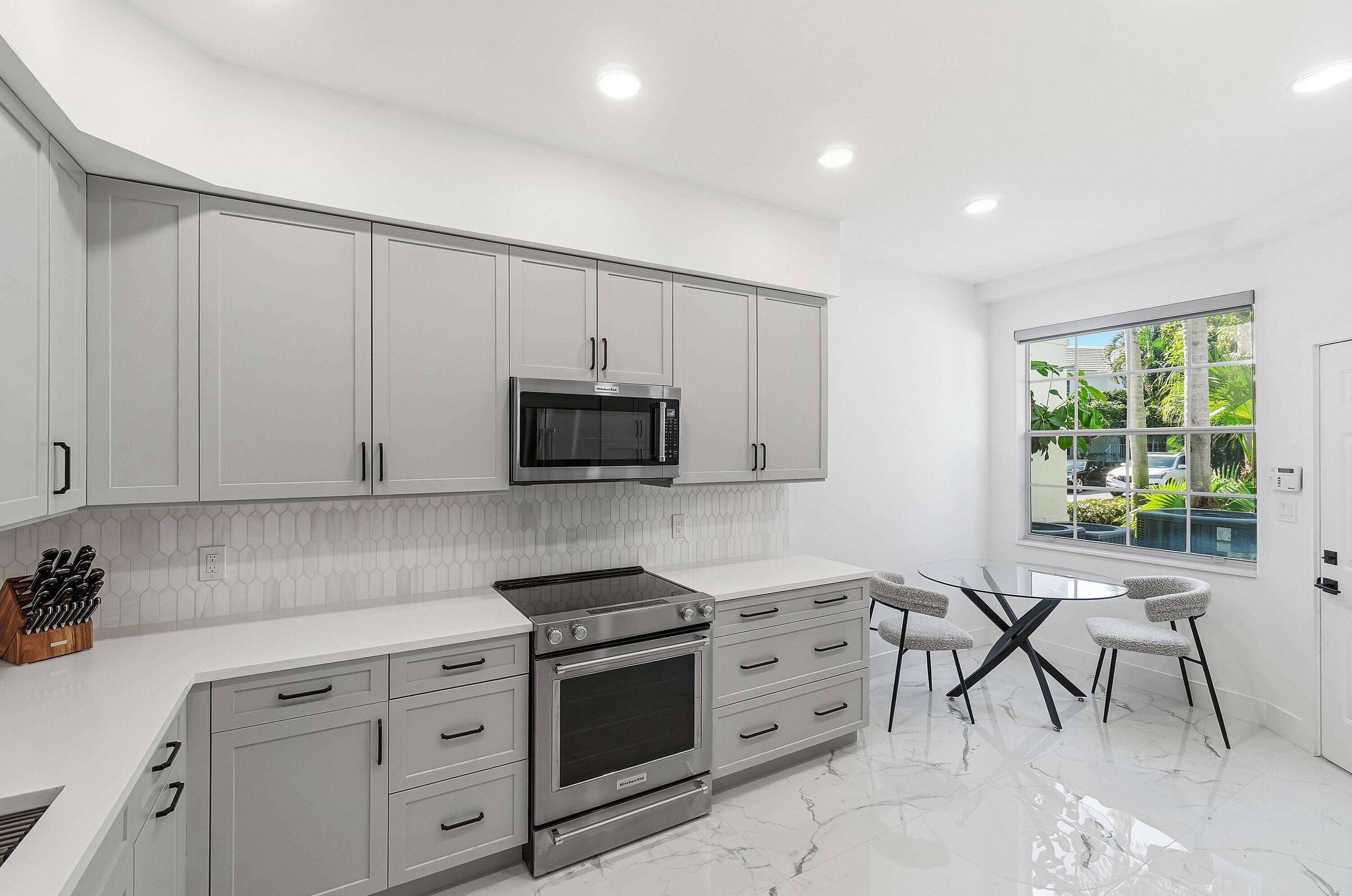 5082 Lake Catalina Drive, Unit A Boca Raton, FL 33496 - Photo 8 of 35 a kitchen with stainless steel appliances granite countertop a stove a sink and a microwave