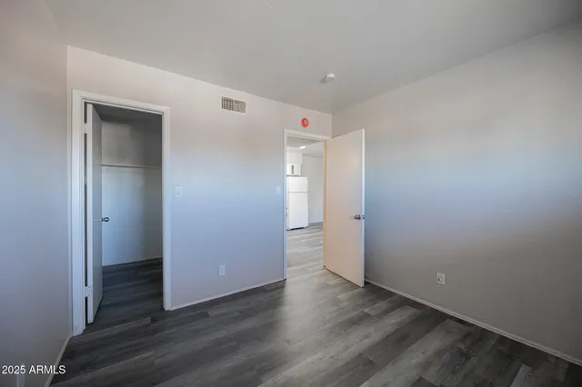 a view of an empty room with wooden floor and closet