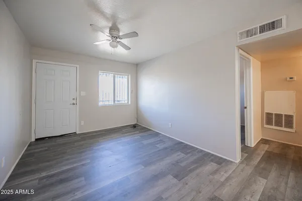 a view of an empty room with wooden floor and a window