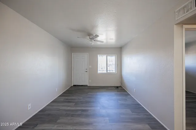 a view of an empty room with a window and wooden floor